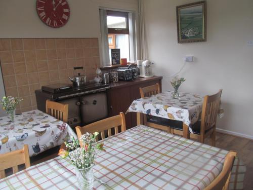 ein Esszimmer mit 2 Tischen und eine Küche in der Unterkunft Drumgauty Cottage in Strabane
