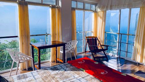 a bedroom with a table and chairs and windows at CHILLAX Resorts Palakkayam THATTU in Paithalmala