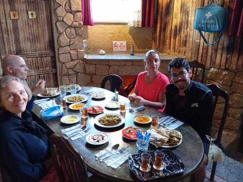 un grupo de personas sentadas alrededor de una mesa comiendo comida en My Grandfather's House en Ḑānā