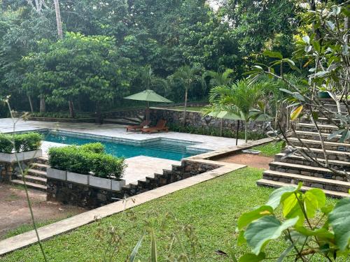 a swimming pool with benches and umbrellas in a yard at Wija House - Unawatuna in Unawatuna