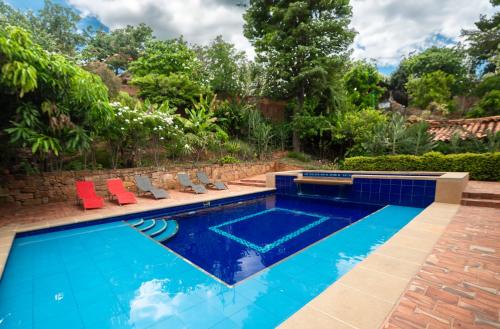 a swimming pool with red chairs in a backyard at Achiotte by Masaya Collection in Barichara