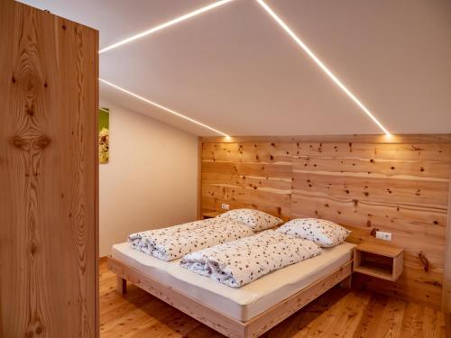 a bed in a room with a wooden wall at Wolfhof_Ritten in Auna di Sopra
