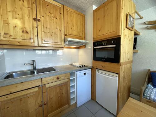 La cuisine est équipée de placards en bois, d'un évier et d'un four micro-ondes. dans l'établissement Appartement classique 2 pièces pour 4 personnes aux Menuires - FR-1-452-233, aux Menuires