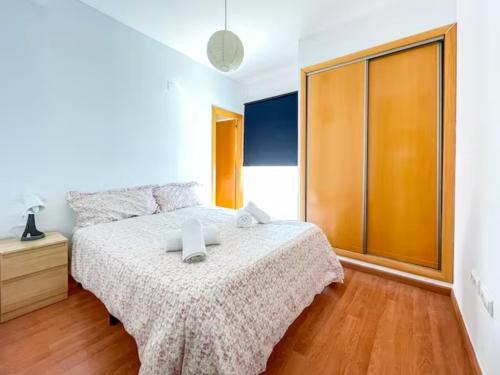 een slaapkamer met een bed en een houten vloer bij Apartamento Cerca del Mar y aeropuerto in Alicante