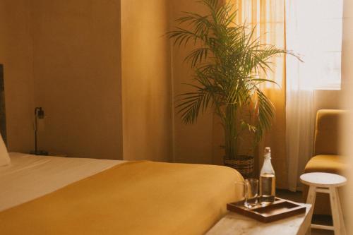 a bedroom with a bed and a table with a bottle and a plant at Gardenia Collective in Tulum