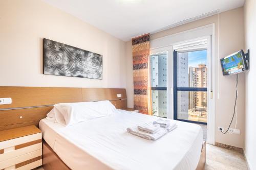 a bedroom with a white bed and a window at Acintur Apartment Levante Beach-Old Town in Benidorm