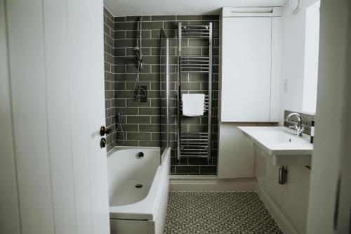a bathroom with a bath tub and a sink at Retreat on the Green in Holt