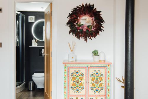a bathroom with a colorful cabinet and a wreath on the wall at Herts Haven, Luxury 2 Bedroom En Suite Barn With Beautiful Views, Free Parking, PS5 & More! in Hemel Hempstead