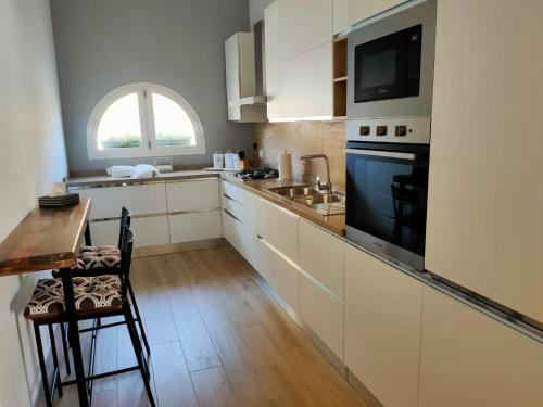 eine Küche mit weißen Schränken, einem Tisch und einem Fenster in der Unterkunft Casa di Mattia in San Cesario di Lecce