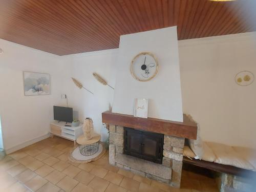 a living room with a fireplace and a clock on the wall at La Parent'aise un brin d'Auvergne 