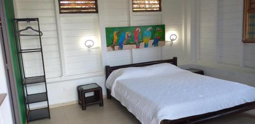 Belle Languette的住宿－Bungalow Ti Bois，卧室配有一张床,墙上挂有绘画作品