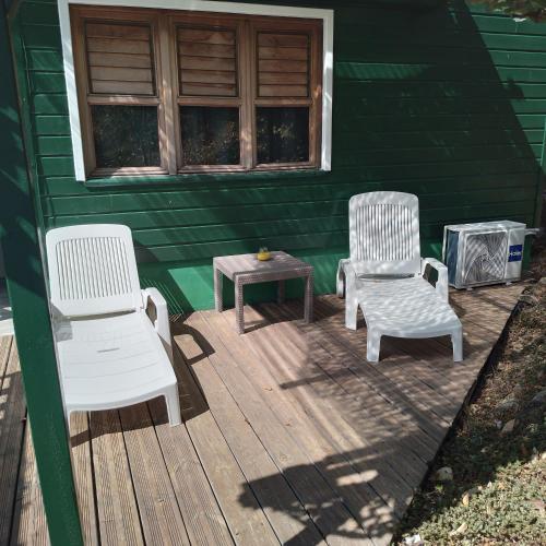 dwa krzesła i stół na drewnianym tarasie w obiekcie Bungalow Ti Bois w mieście Belle Languette