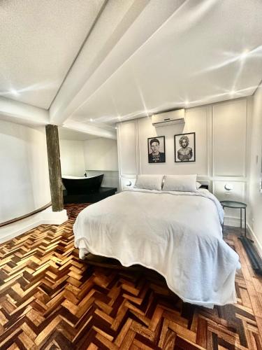a bedroom with a large bed and a wooden floor at Estúdio 196 in Bento Gonçalves