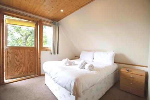 a bedroom with a bed with two stuffed animals on it at Lazy Bear Lodge with Hot Tub - Finlake Resort and Spa in Devon in Chudleigh