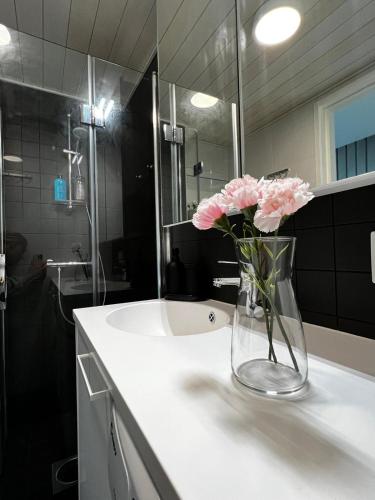 un vase avec des fleurs roses assis sur un comptoir dans une salle de bains dans l'établissement Penthouse Loft - Near the Airport, à Vantaa