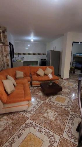 a living room with an orange couch and a kitchen at apartamento para turistas Solangel in San Gil