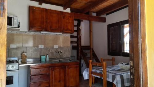 una cocina con armarios de madera, una mesa y una escalera en POSADA LAS MARGARITAS en Santa Rosa de Calamuchita