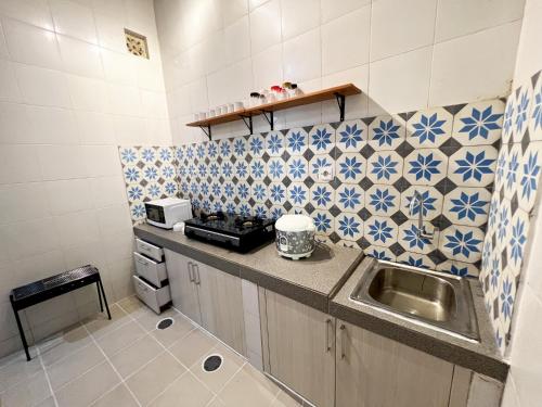a small kitchen with a sink and blue and white tiles at Villaok in Kuta
