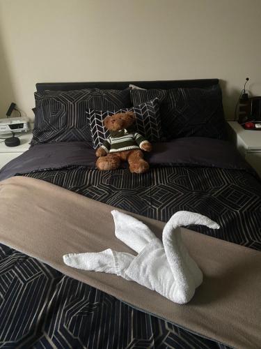 a teddy bear sitting on a bed with a towel at Nice room in Chelsea in London