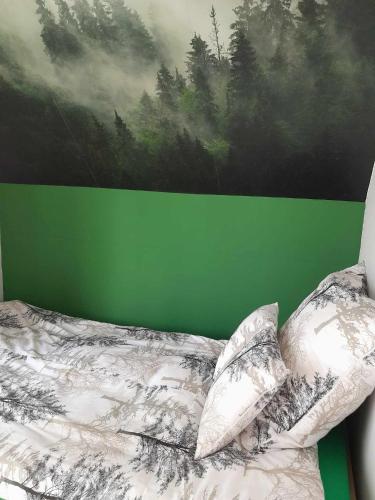 a bedroom with a green wall and a bed with pillows at Przystanek Las in Gąsawa