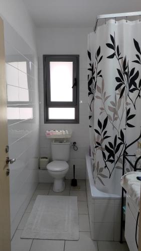 een badkamer met een toilet en een douchegordijn bij Green Park in H̱adera