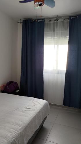 una camera da letto con un letto con tende blu e una finestra di Green Park a Hadera