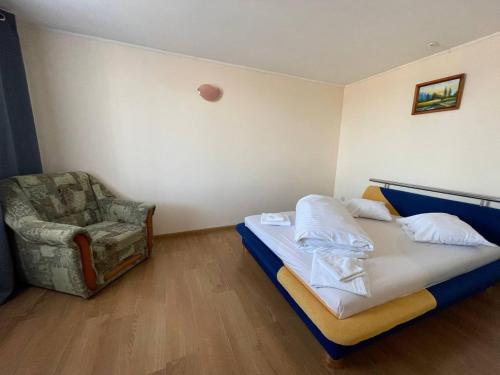 een kleine slaapkamer met een bed en een stoel bij Спортохота in Tsjerkasi