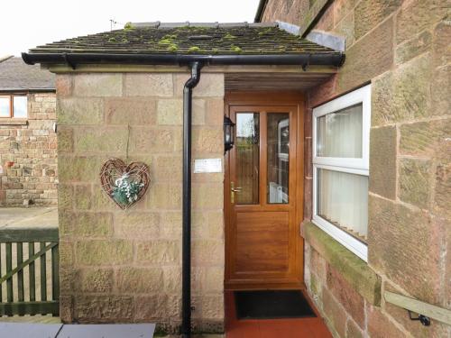 a brick house with a wooden door and a heart on the wall at The Granary in Biddulph