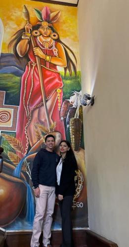 a man and woman standing in front of a painting at Hotel Boutique Spa Villa de Sant in Quito