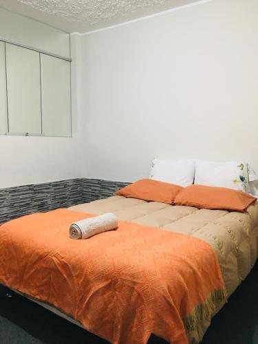 1 dormitorio con 2 camas y manta naranja en Munay, en Tacna