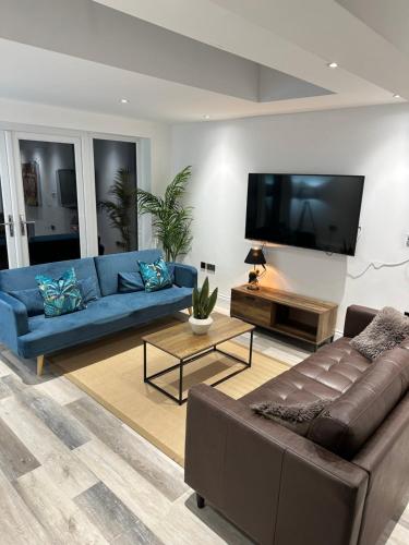 a living room with a blue couch and a flat screen tv at Dora Cottage in Formby