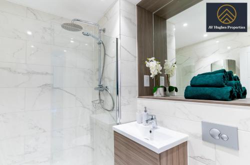 La salle de bains blanche est pourvue d'une douche et d'un lavabo. dans l'établissement Two Bedroom Exquisite by AV Hughes Properties Short Lets & Serviced Accommodation Milton Keynes - For Business & Vacationers, à Milton Keynes