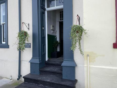 une porte d'entrée bleue d'un bâtiment avec deux plantes en pot dans l'établissement No. 20 The Headland, à Hartlepool