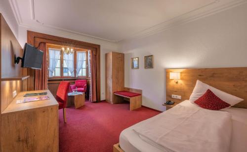 里拉辛根-沃布林根的住宿－克朗酒店，配有一张床和一张书桌的酒店客房