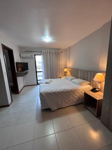 1 dormitorio con 1 cama y TV en Aquarius Flat Studio 601, en Santa Cruz do Sul