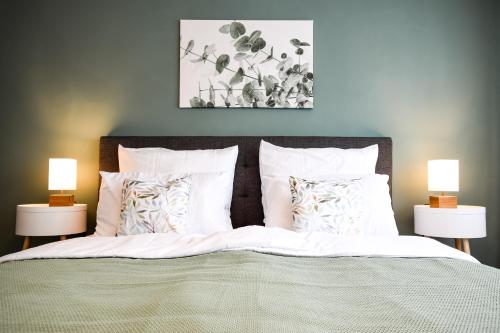 a bed with white sheets and pillows and two lamps at SCANDiC-Apartment - Balkony & Garage, 3Z, 80m2 in Pforzheim