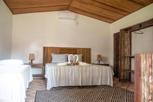 ein Schlafzimmer mit einem Bett mit weißer Bettwäsche und Blumen darauf in der Unterkunft Orla Atins in Atins