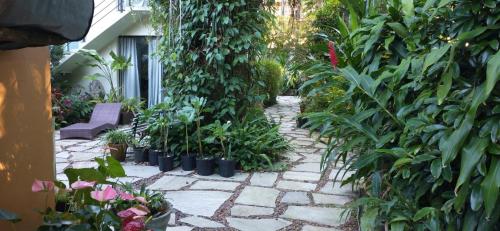 un jardín con plantas y un camino de piedra en Suítes Km18praia en Barra do Una