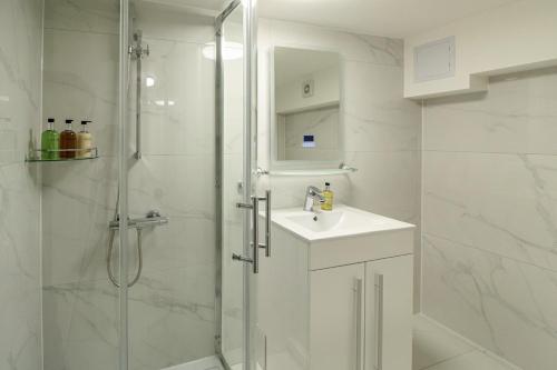 a white bathroom with a shower and a sink at London South Kensington mews house near Natural History Museum and tube in London