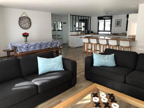 un salon avec deux canapés noirs et une cuisine dans l'établissement Maison proximité Golf et plage de Bréville sur Mer, à Bréville-sur-Mer