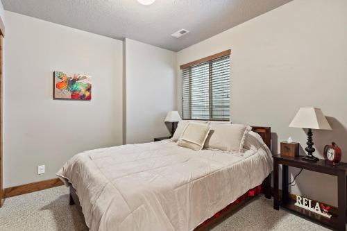 a white bedroom with a bed and a window at Moosehollow Condos in Eden