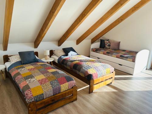 two beds in a room with wooden ceilings at Apartman Detvianka 1 in Detva