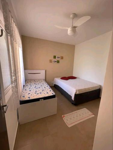 1 dormitorio con 2 camas y ventilador de techo en Praia Martin de Sá SP. en Caraguatatuba