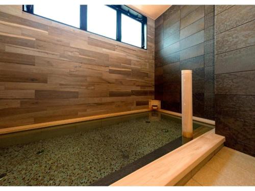 a bathroom with a shower with a wooden wall at QUEEN'S HOTEL CHITOSE - Vacation STAY 67739v in Chitose