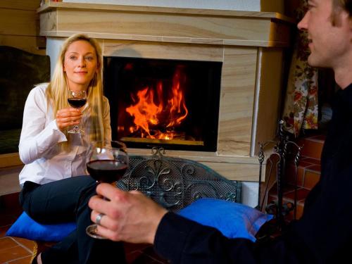 a man and woman drinking wine in front of a fireplace at Hotel Neue Post in Sölden