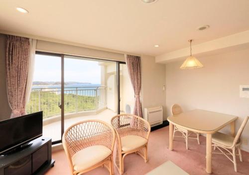 a living room with a table and chairs and a large window at Kamogawa Grand Tower - Vacation STAY 53387v in Kamogawa