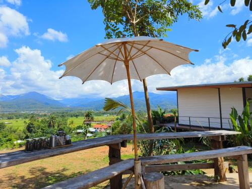 einen Regenschirm auf einer Holzbank in der Unterkunft นะลาวิว รีสอร์ท ปัว Nala View Resort Pua in Pua