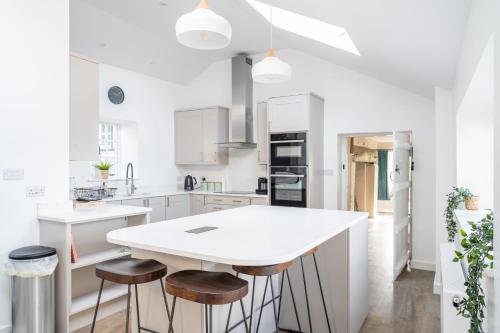 a white kitchen with a white island and stools at Charming Family Farmhouse near Lyme Regis in Axminster
