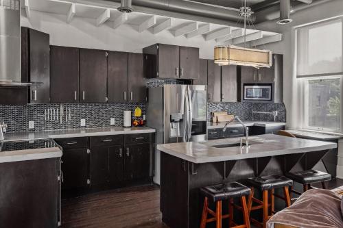 una cucina con armadi in legno e un'isola cucina con sgabelli da bar di Broadway Luxe Loft a Siloam Springs