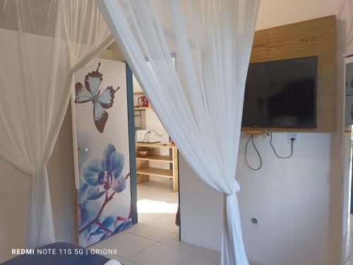 a room with a white curtain and a television at Res. Orion Praia do Espelho in Praia do Espelho